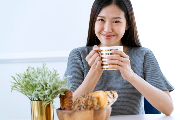 Casual beautiful asian woman enjoy weekend morning withn tea and tablet white room interior background