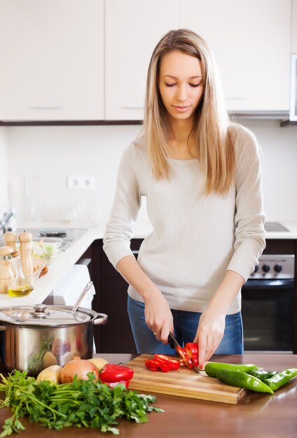 Casual blonde woman slicing red pepper