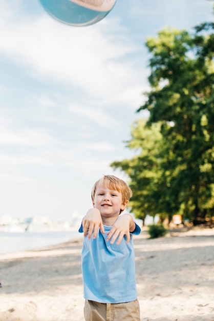 Free photo casual boy throwing beach ball