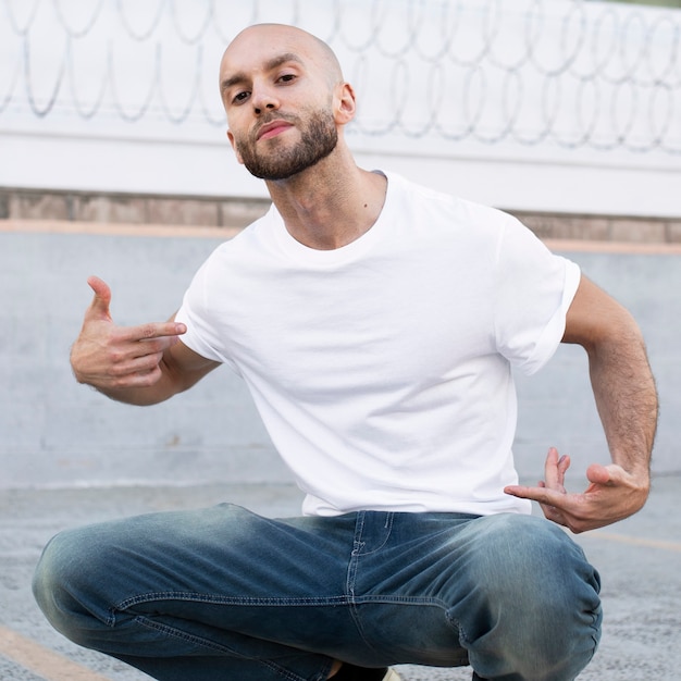 Foto gratuita uomo vestito casual seduto sul servizio fotografico all'aperto sul marciapiede