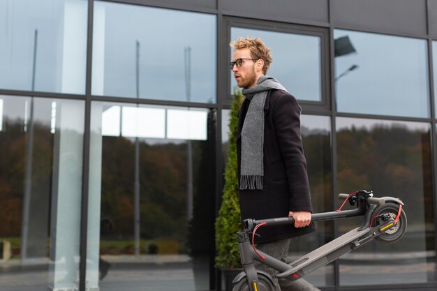 Free photo casual male carrying an electric scooter