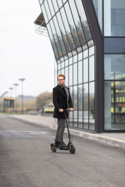 Casual male posing with an electric scooter