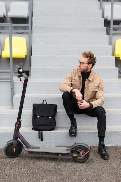 Free photo casual male posing with an electric scooter