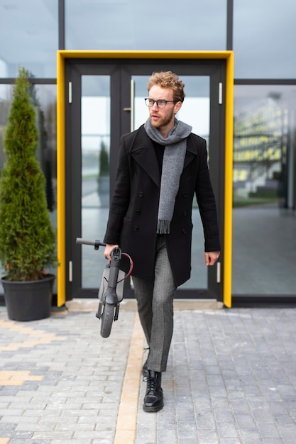 Free photo casual male posing with an electric scooter