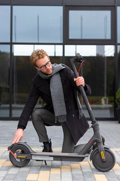 Casual male posing with an electric scooter