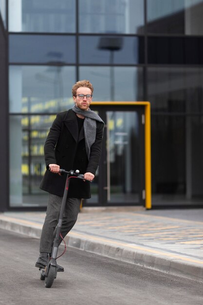 Casual male posing with an electric scooter