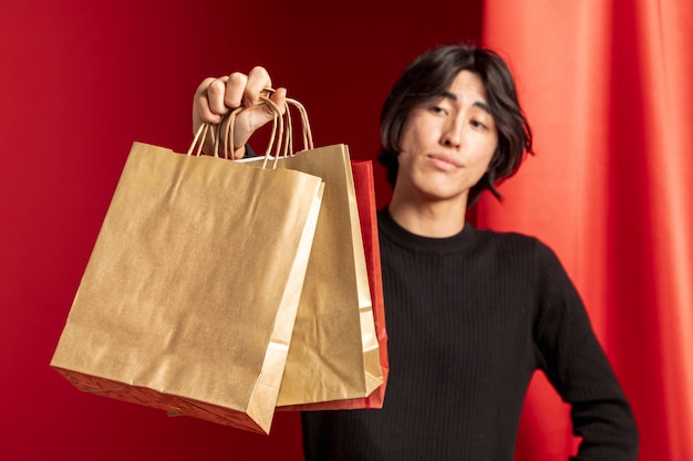 Free photo casual man showing paper shopping bag for chinese new year