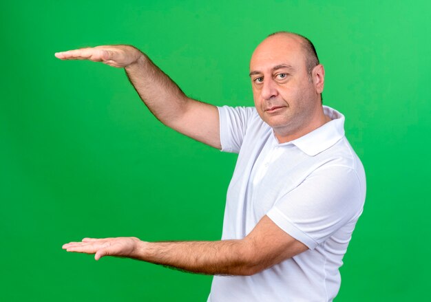 casual mature man showing size isolated on green with copy space