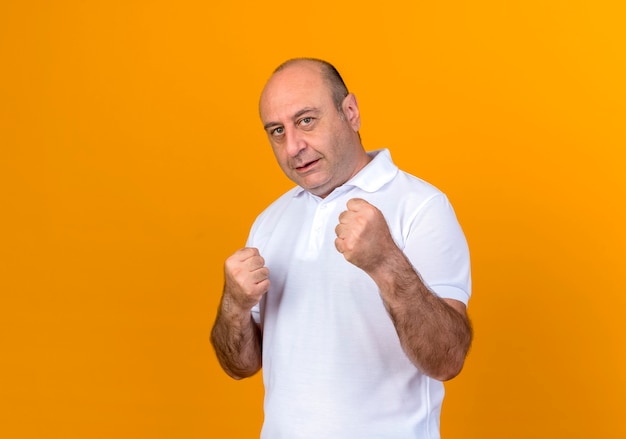 Free photo casual mature man standing in fighting pose isolated on yellow wall