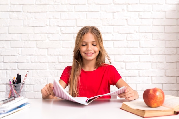 Casual schoolgirl reading workbook