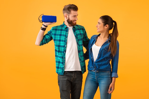 Casual young couple holding wireless speaker listening to music