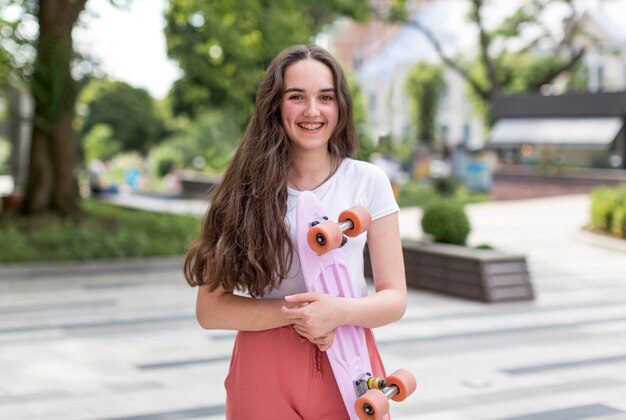 Casual young girl holding her skateboard outdoors