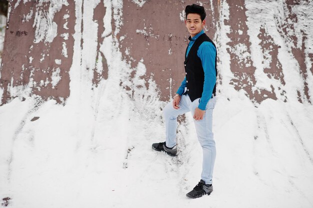 Casual young indian man in blue shirt and black waistcoat posed at winter day