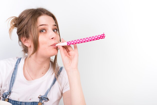 Casual young woman blowing noisemaker