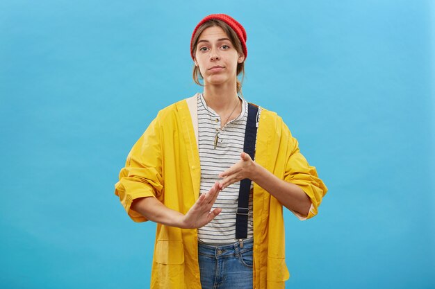 Operaio femminile vestito con indifferenza strofinando le mani dopo aver terminato il suo lavoro isolato sopra la parete blu.