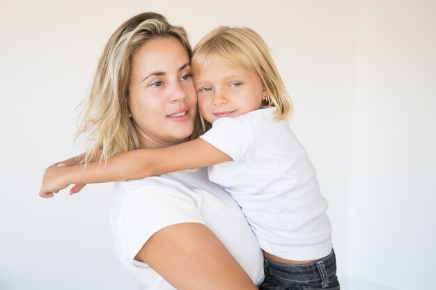 Caucasian attractive mother holding daughter and looking away
