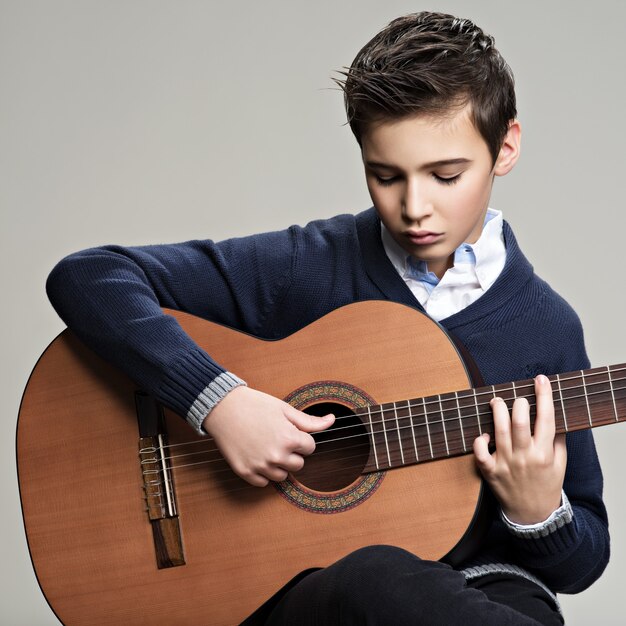 Caucasian  boy playing on acoustic guitar.