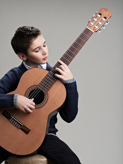 Caucasian  boy playing on acoustic guitar.