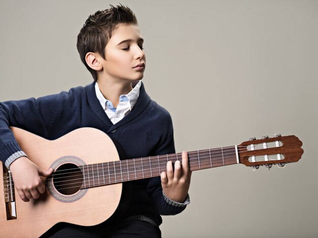 Caucasian  boy playing on acoustic guitar.