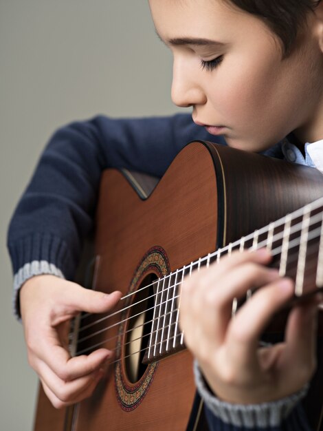 Caucasian  boy playing on acoustic guitar.