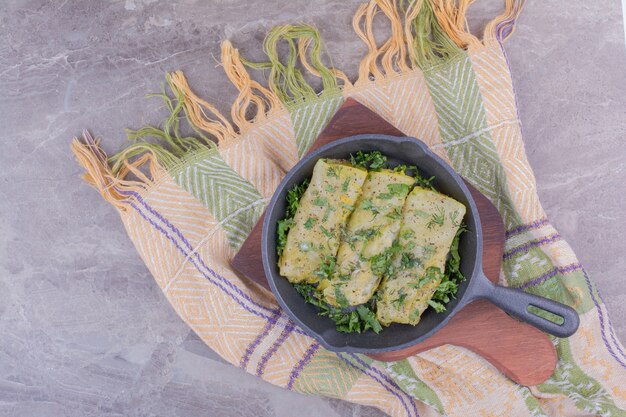 Caucasian cabbage wraps with minced herbs in a black pan.