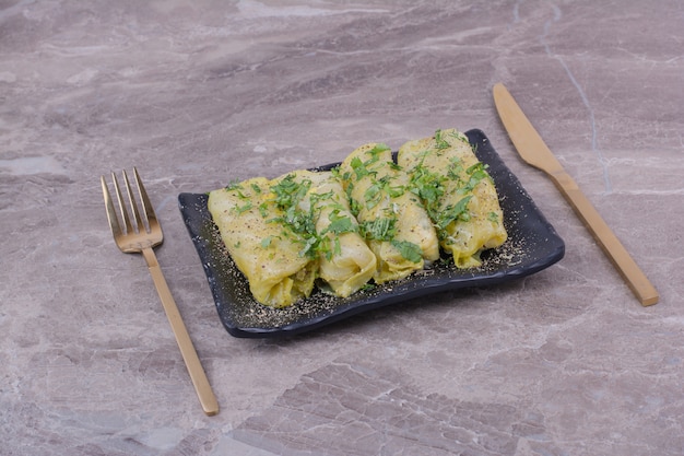 Бесплатное фото Завитушки из кавказской капусты с рубленой зеленью на черном керамическом блюде.