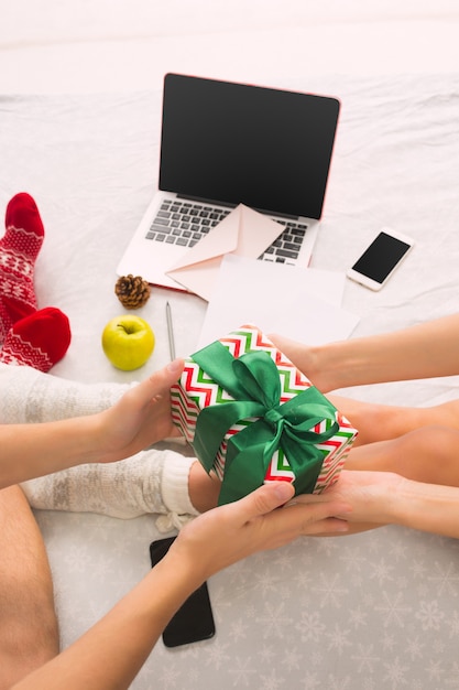 caucasian couple with gift. Laptop and phone for people sitting on the floor at colored socks. Christmas, love, lifestyle concept