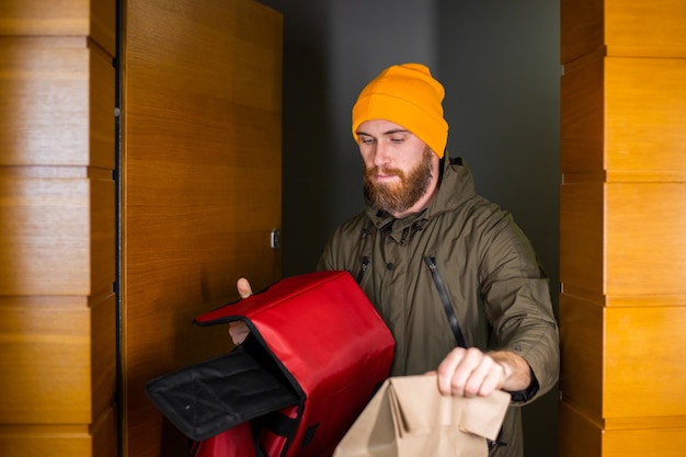 Free photo caucasian deliver man handling box with food inside, give to costumer in doorway. delivery service during covid19.