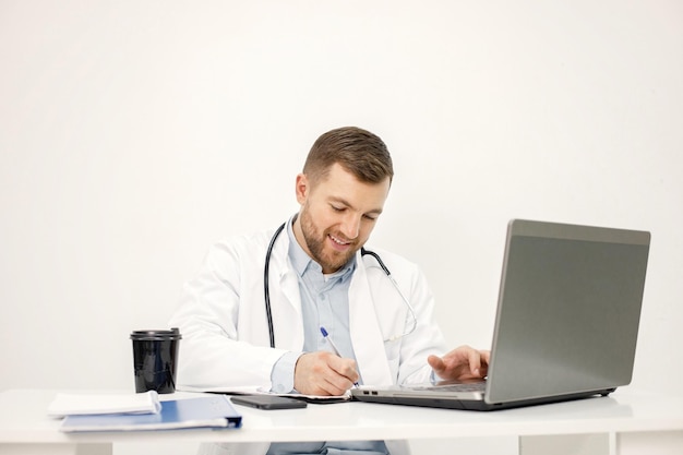 Caucasian doctor sitting at workplace and using laptop