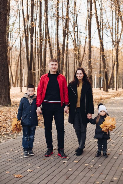 Caucasian family goes for a walk in the autumn park with two children