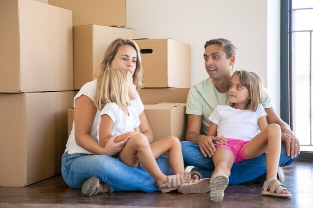 Caucasian family with kids surrounded with boxes full of stuff