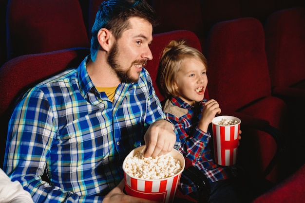 Кавказский отец и сын смотрят фильм в кинотеатре, доме или кинотеатре.