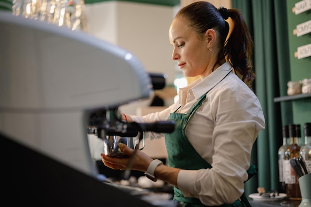 Кавказская женщина-бариста на работе делает кофе