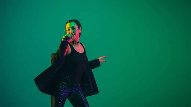 Caucasian female singer portrait isolated on green studio wall