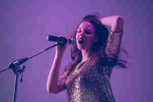 Foto gratuita ritratto di cantante femminile caucasico isolato su studio viola in luce al neon