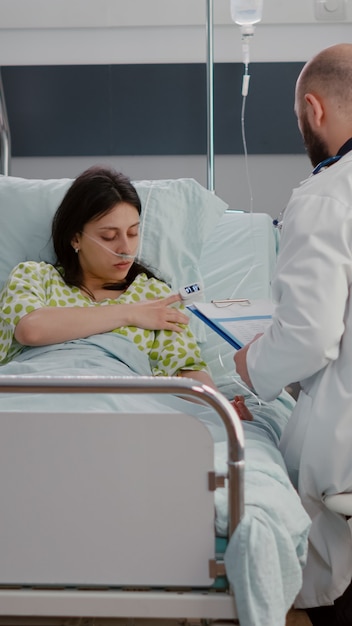 Free photo caucasian female with nasal oxygen tube sitting in bed in hospital ward