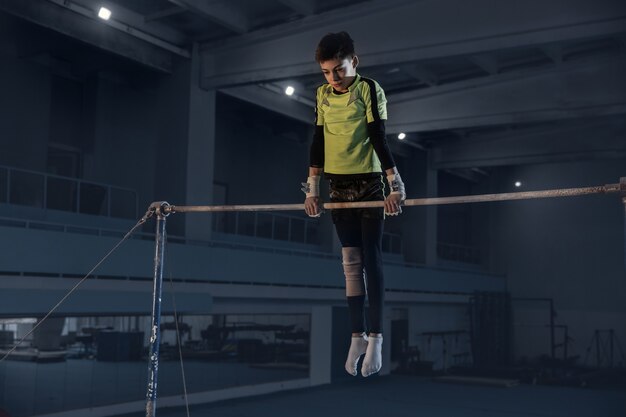 Caucasian fit little boy, athlete in sportswear practicing in exercises for strength, balance.