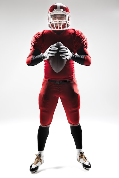 Caucasian fitness man as american football player holding a ball on white background