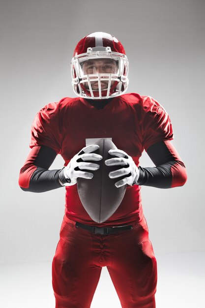 Caucasian fitness man as american football player holding a ball on white