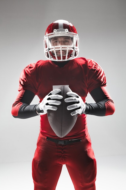 Caucasian fitness man as american football player holding a ball on white