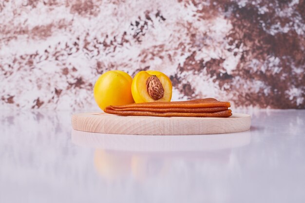 Caucasian fruit lavash with yellow peaches in a white plate on marble.