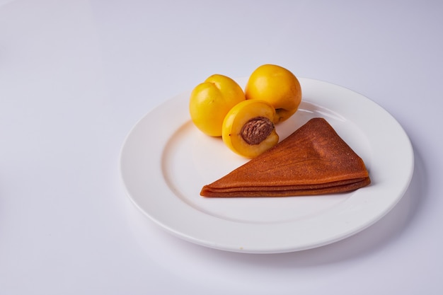 Caucasian fruit lavash with yellow peaches in a white plate.