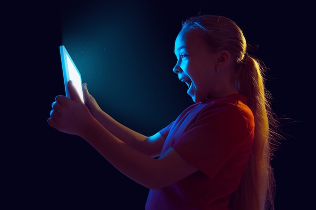 Caucasian girl's portrait isolated on dark in neon light