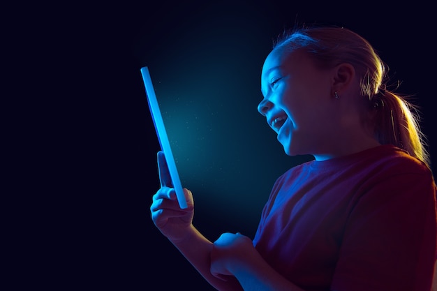 Caucasian girl's portrait isolated on dark studio in neon light