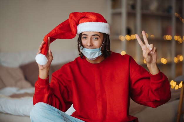 Caucasian guy in face mask and santa claus hat