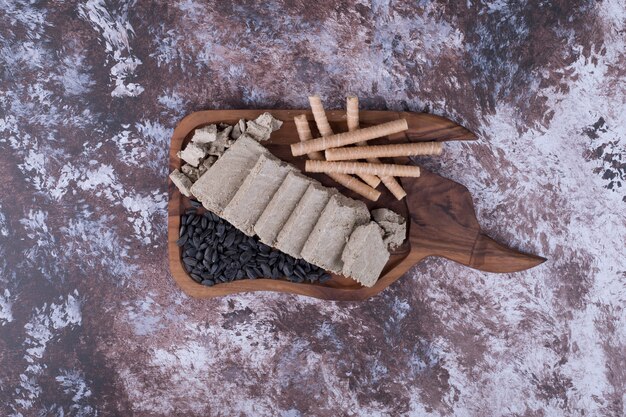 Caucasian halva sliced and served with waffle sticks and sunflower seeds in a wooden platter