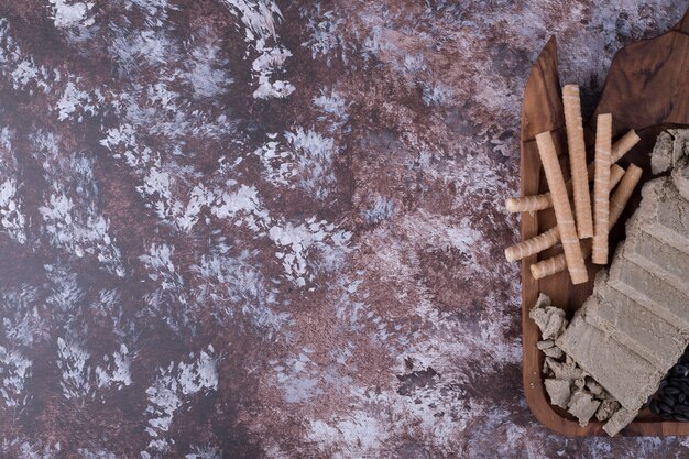 Caucasian halva sliced and served with waffle sticks in a wooden platter