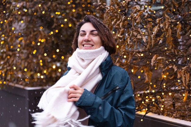 Caucasian happy smiling woman enjoying snow and winter, wearing warm scarf