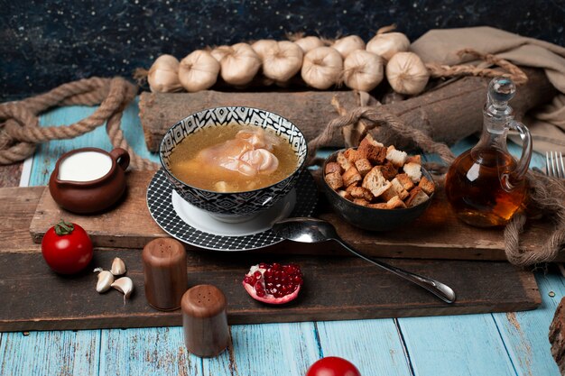 Caucasian khash in bowl with yogurt, crackers and tomatoes