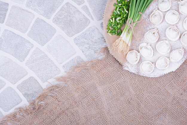 Free photo caucasian khinkali dough on a wooden board with green onions